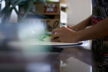 Manos de joven esposa cortando vegetales
