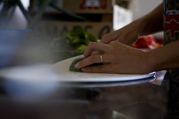 Manos de joven esposa cortando vegetales