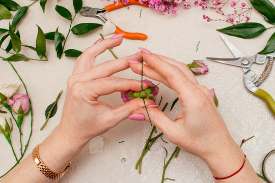 The process of making a bride's wedding wreath from fresh flowers of cream and pink roses,gypsophila and Ruskus leaves.Step-by-step instruction, step 3, top view