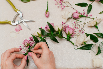 The process of making a bride's wedding wreath from fresh flowers of cream and pink rose,gypsophila and Ruskus leaves.Step-by-step instruction, step 12, top view