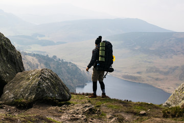 Viajero cargado con mochila grande contemplando un paisaje desde las alturas en Irlanda