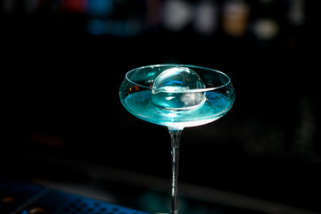 Close-up of very beautiful glass with blue drink stand on bar.