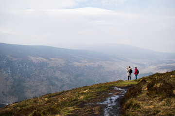 Dos personas contemplando un amplio paisaje en las montañas de Irlanda