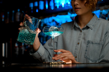 young woman bartender ready to pour cocktail into glass