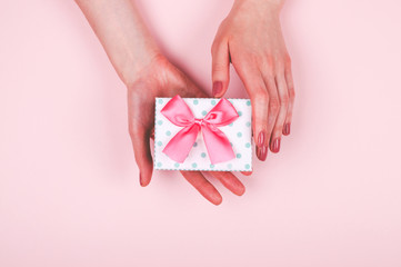 Woman hands with present box on light pink background