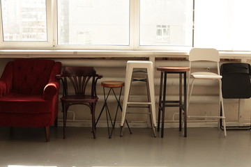 various different chairs stools stand along the wall by the window