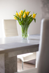 Bukiet żółtych tulipanów w wazonie na stole.