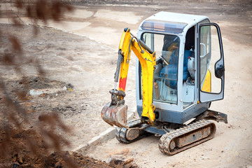 Tracked mini excavator breaks out old curbs before installing new curbs. The concept of using economical and compact equipment - obrazy, fototapety, plakaty