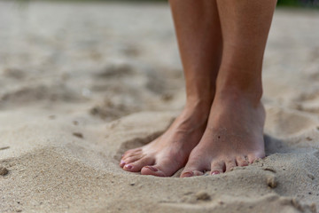 Fototapeta na wymiar female feet on sand at beach in summer in sunny weather