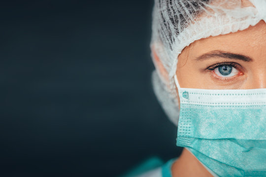 Protection against contagious disease, coronavirus. Female doctor wearing hygienic face surgical medical mask to prevent infection, respiratory illness as flu, 2019-nCoV. Studio photo black background