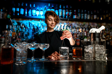 Young lady holds in her hand special long spoon for mixing cocktails.