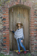 Portrait of a girl on a background of an old brick wall and a wooden door.