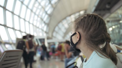 Children girl kid caucasian at airport with wearing protective medical mask on head against background of plane. Concept health virus protection coronavirus epidemic sars-cov-2 covid-19 2019-ncov.