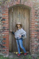 Portrait of a girl on a background of an old brick wall and a wooden door.