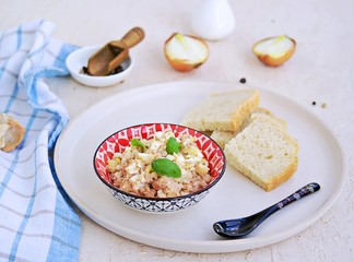 Appetizer, salad of canned cod liver, boiled egg and onions in a colored ceramic bowl on a light concrete background. Served with fresh white bread. Appetizer Recipes