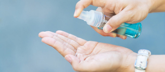 woman hand spraying alcohol sanitizer bottle dispenser, against Novel coronavirus or Corona Virus Disease (Covid-19) at public outdoor. Antiseptic, Hygiene and Healthcare concept