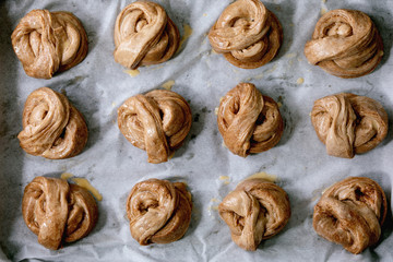 Ready to bake traditional Swedish cinnamon sweet buns Kanelbulle on oven tray cover by baking paper. Flat lay, space