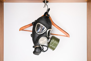 Coronavirus. A black gas mask hangs on the clothes hanger in an empty wardrobe.