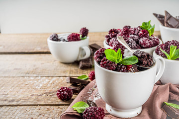Homemade chocolate mug cake with blackberry. Breakfast easy snack recipe, chocolate non dairy cake in mugs, with blackberry, sugar powder and mint, wooden rustic background