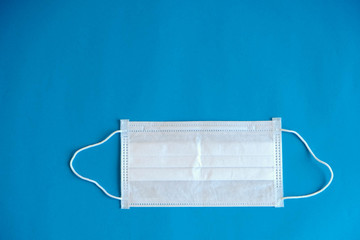 Medical mask on blue background. Procedure mask from bacteria. Protection concept. Top view. Copy, empty space for text