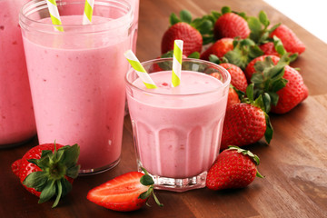 Glass of fresh strawberry shake, smoothie or milkshake and fresh strawberries on table. Healthy food and drink concept