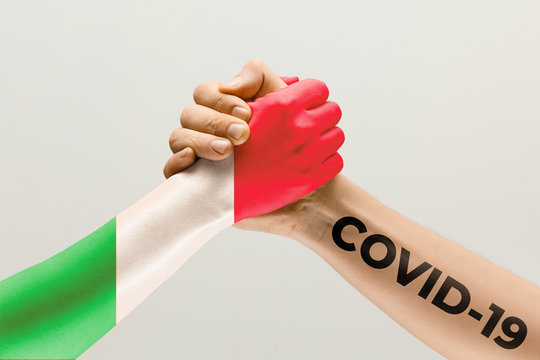 Human hands colored in flag of Italy and coronavirus - concept of spreading of virus. Hands shaking is danger, the way of wordwide epidemic. Stay safe. Prevention, safety, pandemic spread concept.