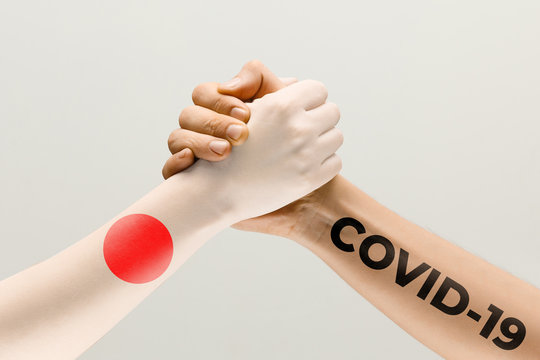 Human hands colored in flag of Japan and coronavirus - concept of spreading of virus. Hands shaking is danger, the way of wordwide epidemic. Stay safe. Prevention, safety, pandemic spread concept.