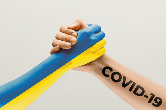 Human hands colored in flag of Ukraine and coronavirus - concept of spreading of virus. Hands shaking is danger, the way of wordwide epidemic. Stay safe. Prevention, safety, pandemic spread concept.