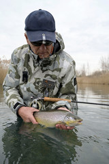 Naklejka premium catch of a beautiful brown trout with fly