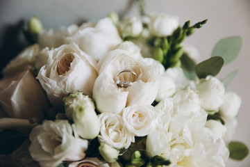 wedding ring lies on a bouquet of white flowers and greenery