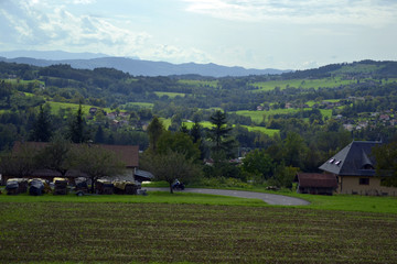Obraz premium Beautiful alpine landscape, very green, at the beginning of autumn. There is a biker in the loop of a bend.