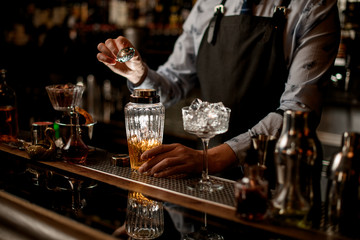 Barman at bar preparing cocktail in glassy shaker