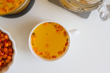 Vitamin useful sea buckthorn tea in a glass teapot with fresh sea buckthorn berries, orange, cinnamon sticks and honey. The concept of rest, relaxation. top view with a copy of the space