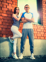 Happy young couple standing outside on a modern brick house background.