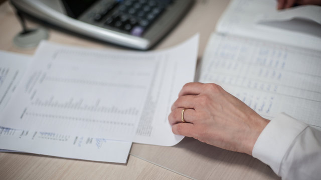  Close-up of female accountant hands, calculates and research the financial data position of the company and planning the economy financial profit or loss of bank accounts