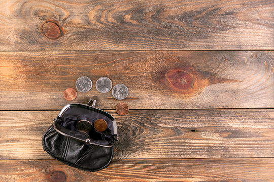 Open black leather pocket wallet with coins one cent and a quarter dollar nearby. Financial crisis, poverty, lack of money. On wooden background or table. Flat lay. Top view.