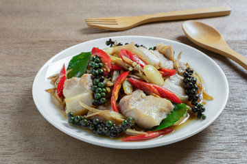 close up of stir fried sizzle pork belly in a ceramic dish on wooden table. asian homemade style food concept.