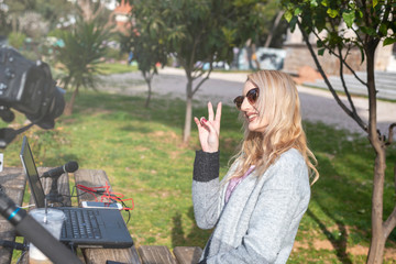 Naklejka premium Female blond you tuber with her equipment in action outdoors