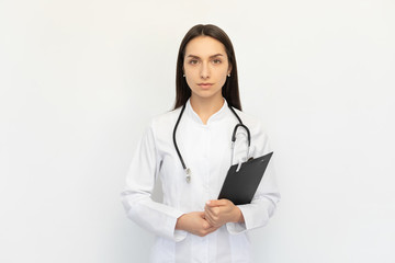 Friendly female doctor smiling serious holding a folder in her hands, a stethoscope on her neck