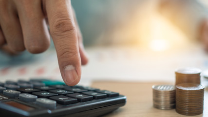 The man's finger that presses the calculator to calculate and analyze income and expenses the...