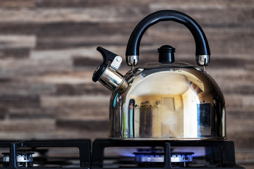 A metal silver teapot on a gas stove in the kitchen