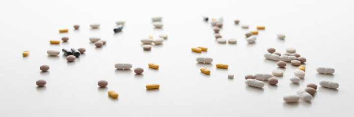 White background with scattered tablets. Bright medical background. Minimal composition. Isolated. Panoramic photo
