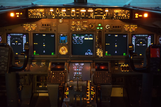 Cockpit (flight deck) of a modern commercial passenger jet aircraft showing the control columns (yoke) with instruments in the background. Glass cockpit. Aviation concept.