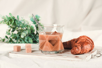 A cup of cold coffee with cream and croissan