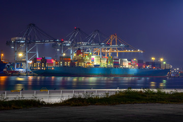 Logistics and container loading by large barges by sea in a harbor full of containers waiting to be transported