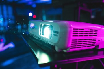 Closeup of a projector under the colorful lights with a blurry background