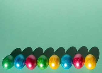 Colorful easter eggs on mint color background. Happy Easter composition. Copy space.