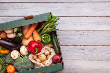 Fresh organic vegetable delivery box on a wooden background - obrazy, fototapety, plakaty