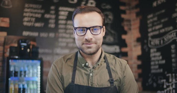 Portrait of happy barista standing at trendy coffee shop