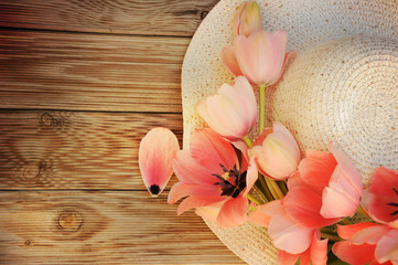 Spring flowers tulips with a straw sun hat